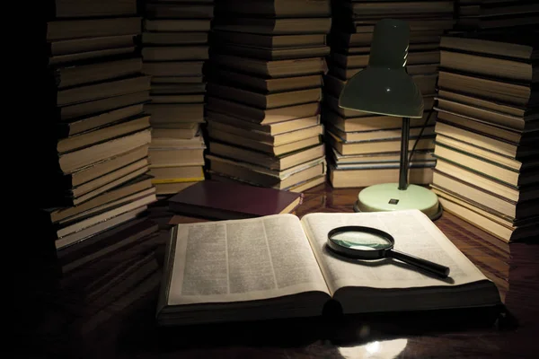 La lámpara y el libro sobre la mesa. Leer un libro con la iluminación de la lámpara en la oscuridad. Libros sobre mesa de madera bajo luz de lámpara — Foto de Stock