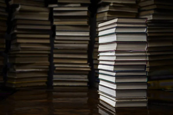 Montón de libros en la mesa de la biblioteca. pila de libros sobre escritorio de madera sobre fondo de libros — Foto de Stock