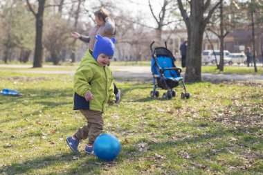 Young toddler playing with an ball in a park. The boy is playing soccer in the park. Happy kid is playing football