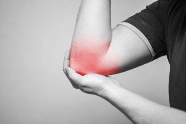 Dirseğinde ağrı olan bir adam. İnsan vücudunda kırmızı noktalı gri bir arka planda ache. Ağrı kesici kavramı