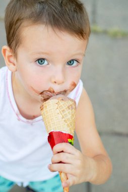 Dondurma yiyen tatlı, küçük çocuk. Kirli suratlı ve dondurma yiyen çocuk. Mutlu çocuk dondurma yiyor..