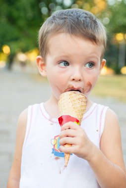 Dondurma yiyen tatlı, küçük çocuk. Kirli suratlı ve dondurma yiyen çocuk. Mutlu çocuk dondurma yiyor..