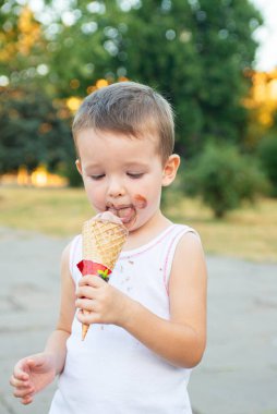 Dondurma yiyen tatlı, küçük çocuk. Kirli suratlı ve dondurma yiyen çocuk. Mutlu çocuk dondurma yiyor..