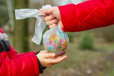 Bir yetişkinin plastik torbasında bir küreye uzanan küçük bir çocuğun eli. Böylece geleceği için dünyaya göz kulak olabilir. Dünyayı kurtar. Dünya Çevre Günü.