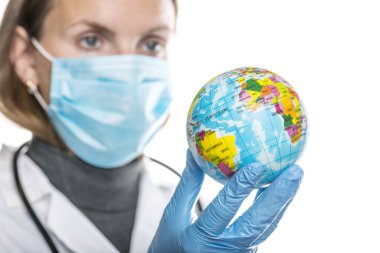 Koruyucu tıbbi maskeli ve eldivenli kadın doktor dünyayı tutuyor. Salgın ve küresel virüs enfeksiyonu kavramı.