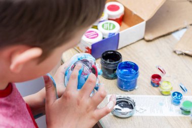 Çocuk Paskalya yumurtalarını boyuyor. Çocuk masada oturuyor ve coşkuyla yaratıcılıkla meşgul, Paskalya için hazırlanıyor..