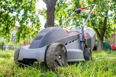 Çim biçme makinesi ağaçların arka planında. Çim biçme makinesinin açık hava çekimi.