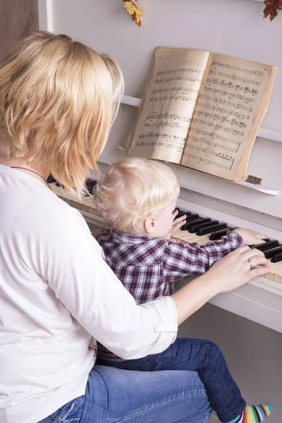 Мама учит маленького ребенка играть на пианино. — стоковое фото