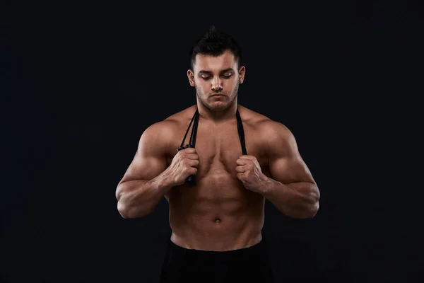 Muscular bodybuilder with jump rope on black background.Strong a — Stock Photo, Image