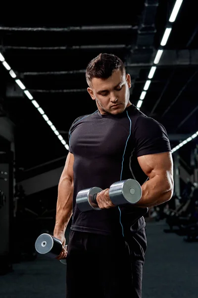 Muscular culturista haciendo ejercicios con mancuerna en gimnasio.Fuerte — Foto de Stock