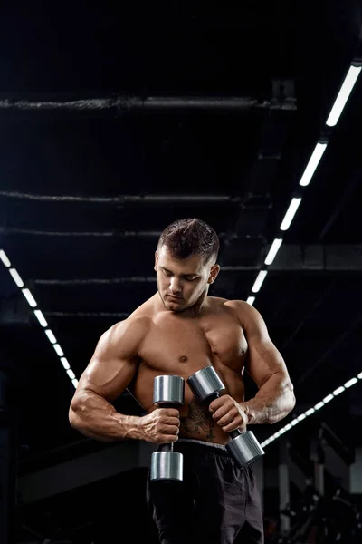 Muscular culturista haciendo ejercicios con mancuerna en gimnasio.Fuerte — Foto de Stock