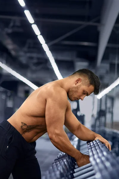 Muscular culturista en el gimnasio tomar mancuerna de bastidor de mancuerna. —  Fotos de Stock