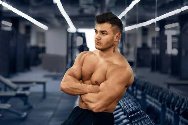 Muscular culturista en el gimnasio cerca del bastidor de mancuerna. Fuerte atlético m — Foto de Stock