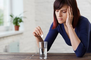Güçlü baş ağrısı muzdarip, parmak onun tapınaklar holding ve ağrı, gözlerinden kapanış genç kadın ilaç almak için prepairing. Şiddetli migren. Aspirin