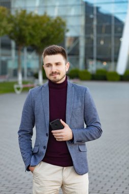 Sıradan giyinmiş, elinde akıllı telefon tutan yakışıklı bir adamın portresi. Genç iş adamı önemli telefon görüşmelerinin sonuçlarını analiz eder. İş merkezinin yakınındaki caddede duran genç adam..
