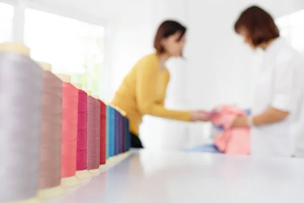 Reihe von bunten Nähgarnspulen auf einem weißen Tisch. — Stockfoto