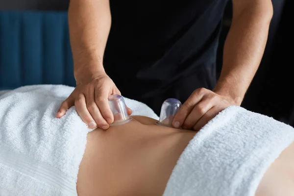 Joven hermosa mujer disfrutando de ventosas de masaje en spa.Professional masajista está tratando a una paciente femenina en apartment.Relaxation, belleza, cuerpo y el tratamiento de la cara concept.Home masaje —  Fotos de Stock