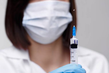 Tıbbi enjeksiyon, hastalıklar, sağlık, bilim, diyabet. Doktor ya da hemşire, elinde enjeksiyona hazırlanan sıvı aşılarla bir şırınga tutuyor. Tıbbi ekipman. Beyaz üniformalı, cüppeli insanlar.