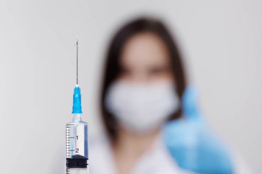 Tıbbi enjeksiyon, hastalıklar, sağlık, bilim, diyabet. Doktor ya da hemşire, elinde enjeksiyona hazırlanan sıvı aşılarla bir şırınga tutuyor. Tıbbi ekipman. Beyaz üniformalı, cüppeli insanlar.