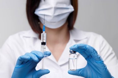 Tıbbi enjeksiyon, hastalıklar, sağlık, bilim, diyabet. Doktor ya da hemşire, elinde enjeksiyona hazırlanan sıvı aşılarla bir şırınga tutuyor. Tıbbi ekipman. Beyaz üniformalı, cüppeli insanlar.