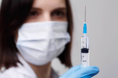 Tıbbi enjeksiyon, hastalıklar, sağlık, bilim, diyabet. Doktor ya da hemşire, elinde enjeksiyona hazırlanan sıvı aşılarla bir şırınga tutuyor. Tıbbi ekipman. Beyaz üniformalı, cüppeli insanlar.