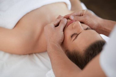 Genç güzel kadın anti-aging yüz masaj zevk. Erkek terapist kadın istemciye baş masajı yapma. Profesyonel masör. Gevşeme, güzellik, spa, vücut ve yüz tedavi kavramı