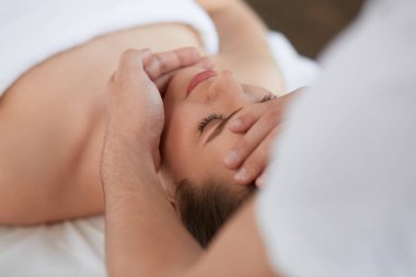 Genç güzel kadın anti-aging yüz masaj zevk. Erkek terapist kadın istemciye baş masajı yapma. Profesyonel masör. Gevşeme, güzellik, spa, vücut ve yüz tedavi kavramı