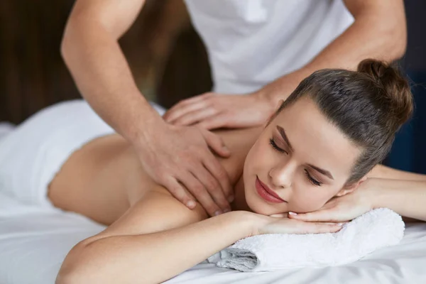 Ung vacker kvinna njuter av rygg och shouders massage i spa.Professionell massage terapeut behandlar en kvinnlig patient i lägenhet.Avkoppling, skönhet, kropp och ansikte behandlingskoncept.Hem massage — Stockfoto