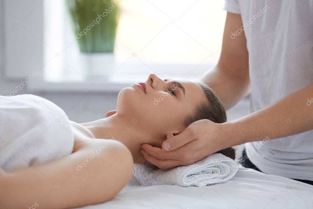 Young beautiful woman enjoying anti-aging facial massage.Male therapist making head massage to female client.Professional masseur.Relaxation,beauty,spa,body and face treatment concept