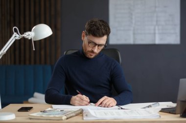 Ofiste planlarla çalışan bir mimar. Mühendis mimari planı inceliyor, bir inşaat projesi çiziyor. İş yerinde oturan sakallı yakışıklı bir adamın portresi. İş inşa kavramı