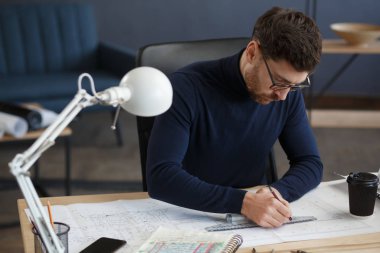 Ofiste planlarla çalışan bir mimar. Mühendis mimari planı inceliyor, bir inşaat projesi çiziyor. İş yerinde oturan sakallı yakışıklı bir adamın portresi. İş inşa kavramı
