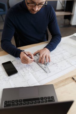 Ofiste planlarla çalışan bir mimar. Mühendis mimari planı inceliyor, bir inşaat projesi çiziyor. İş yerinde oturan sakallı yakışıklı bir adamın portresi. İş inşa kavramı