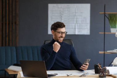 Genç adam akıllı telefon kullanıyor ve gülümsüyor. Mutlu iş adamı cep telefonu uygulamaları kullanıyor, mesaj atıyor, internette geziniyor, akıllı telefona bakıyor. Mobil aygıtlarla çalışan gençlerin kavramı