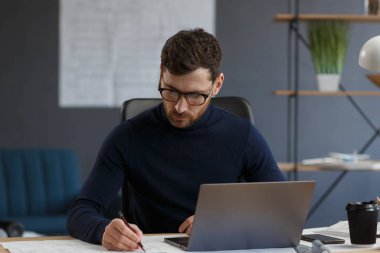 Ofiste planlarla çalışan bir mimar. Mühendis mimari planı inceliyor, bir inşaat projesi çiziyor. İş yerinde oturan sakallı yakışıklı bir adamın portresi. İş inşa kavramı