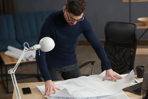 Arquitecto trabajando en la oficina con planos. Ingeniero inspeccionar plan arquitectónico, bosquejando un proyecto de construcción. Retrato de hombre barbudo guapo sentado en el lugar de trabajo. Concepto de construcción empresarial — Foto de Stock