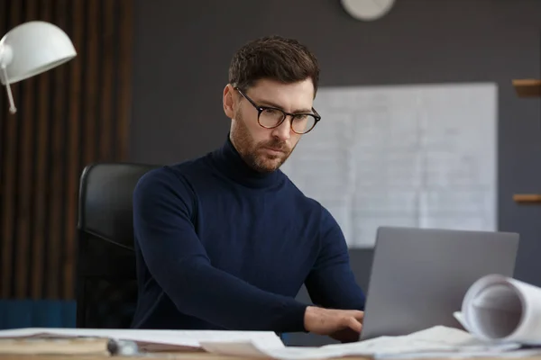 Arquitecto trabajando en la oficina con planos. Ingeniero inspeccionar plan arquitectónico, bosquejando un proyecto de construcción. Retrato de hombre barbudo guapo sentado en el lugar de trabajo. Concepto de construcción empresarial — Foto de Stock