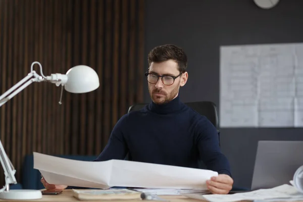 Arquitecto trabajando en la oficina con planos. Ingeniero inspeccionar plan arquitectónico, bosquejando un proyecto de construcción. Retrato de hombre barbudo guapo sentado en el lugar de trabajo. Concepto de construcción empresarial — Foto de Stock