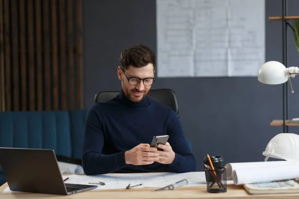 Joven usando smartphone y sonriendo. Feliz hombre de negocios utilizando aplicaciones de teléfono móvil, mensaje de texto, navegación por Internet, mirando el teléfono inteligente. Concepto de jóvenes que trabajan con dispositivos móviles — Foto de Stock