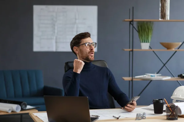 Joven usando smartphone y sonriendo. Feliz hombre de negocios utilizando aplicaciones de teléfono móvil, mensaje de texto, navegación por Internet, mirando el teléfono inteligente. Concepto de jóvenes que trabajan con dispositivos móviles — Foto de Stock