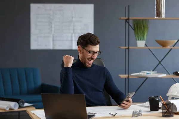 Joven usando smartphone y sonriendo. Feliz hombre de negocios utilizando aplicaciones de teléfono móvil, mensaje de texto, navegación por Internet, mirando el teléfono inteligente. Concepto de jóvenes que trabajan con dispositivos móviles — Foto de Stock