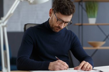 Ofiste planlarla çalışan bir mimar. Mühendis mimari planı inceliyor, bir inşaat projesi çiziyor. İş yerinde oturan sakallı yakışıklı bir adamın portresi. İş inşa kavramı