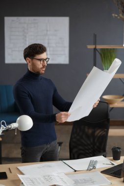 Ofiste planlarla çalışan bir mimar. Mühendis mimari planı inceliyor, bir inşaat projesi çiziyor. İş yerinde oturan sakallı yakışıklı bir adamın portresi. İş inşa kavramı