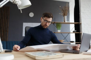 Ofiste planlarla çalışan bir mimar. Mühendis mimari planı inceliyor, bir inşaat projesi çiziyor. İş yerinde oturan sakallı yakışıklı bir adamın portresi. İş inşa kavramı