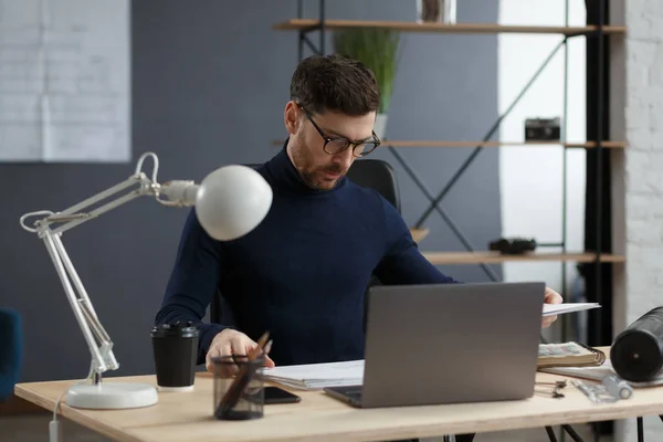 Arquitecto trabajando en la oficina con planos. Ingeniero inspeccionar plan arquitectónico, bosquejando un proyecto de construcción. Retrato de hombre barbudo guapo sentado en el lugar de trabajo. Concepto de construcción empresarial — Foto de Stock