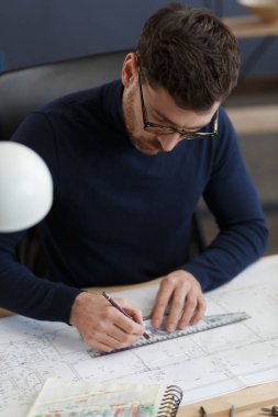 Ofiste planlarla çalışan bir mimar. Mühendis mimari planı inceliyor, bir inşaat projesi çiziyor. İş yerinde oturan sakallı yakışıklı bir adamın portresi. İş inşa kavramı