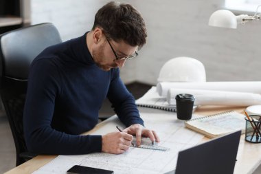 Ofiste planlarla çalışan bir mimar. Mühendis mimari planı inceliyor, bir inşaat projesi çiziyor. İş yerinde oturan sakallı yakışıklı bir adamın portresi. İş inşa kavramı
