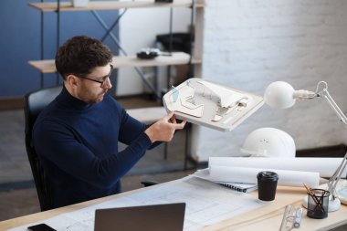 Ofiste çalışan mimar 3D model bir bina. Mühendis bina planını inceliyor, inşaat projesi için yeni fikirler arıyor. İş yerindeki yakışıklı sakallı adam. İş inşa kavramı