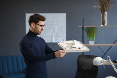 Ofiste çalışan mimar 3D model bir bina. Mühendis bina planını inceliyor, inşaat projesi için yeni fikirler arıyor. İş yerindeki yakışıklı sakallı adam. İş inşa kavramı