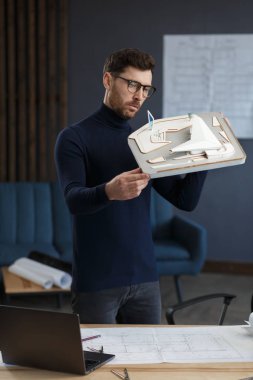 Ofiste çalışan mimar 3D model bir bina. Mühendis bina planını inceliyor, inşaat projesi için yeni fikirler arıyor. İş yerindeki yakışıklı sakallı adam. İş inşa kavramı