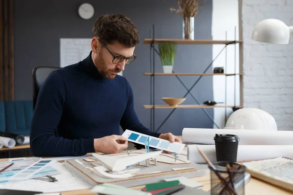 Architekt im Büro mit Farbpalette. Ingenieur wählen Farben für Gebäude mit Farbmustern, auf der Suche nach neuen Ideen für das Bauprojekt. Porträt eines gutaussehenden bärtigen Mannes am Arbeitsplatz — Stockfoto